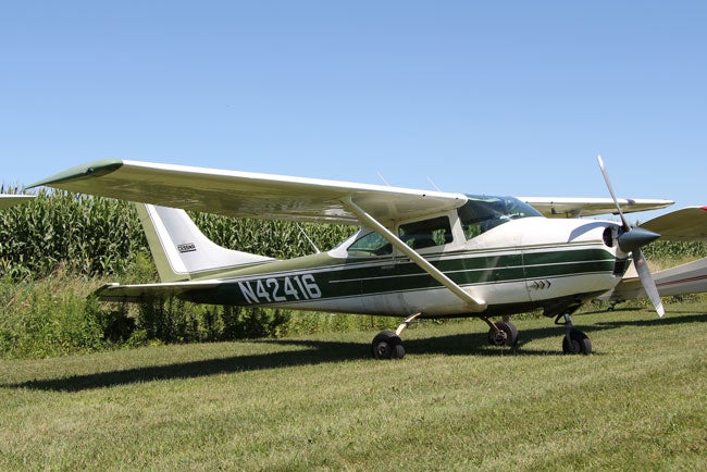 White and green Cessna 182 Skylane parked in field