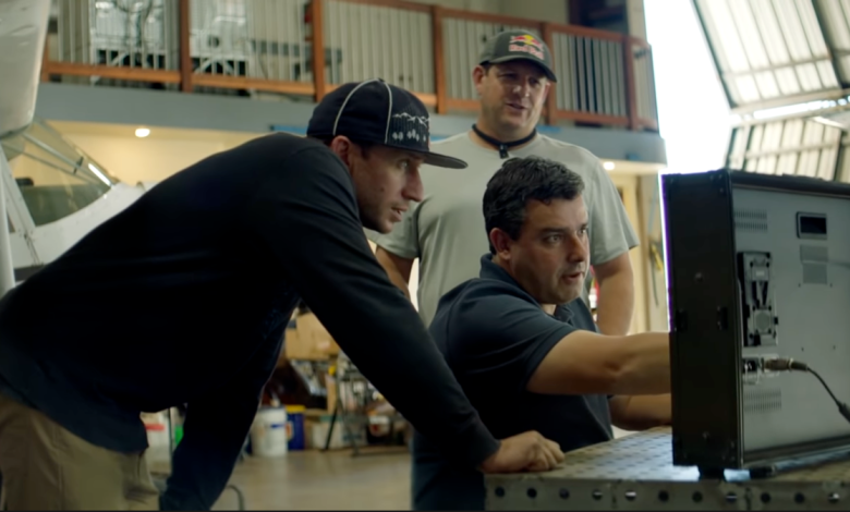Red Bull Plane Swap pilots Andy Farrington (at left) and Luke Aikins (far right) study the aerodynamics of the planes' speed brakes with aerodynamicist Dr. Paulo Iscold. - Red Bull Plane Swap Debacle