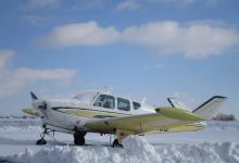 A Beechcraft Bonanza sits in the snow.