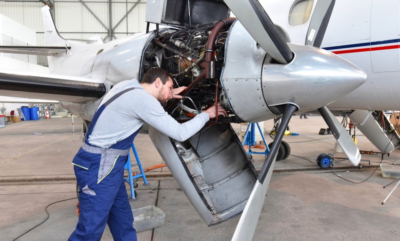 Aircraft mechanic repairs an engine in an airport hangar. [Credit: Shutterstock]