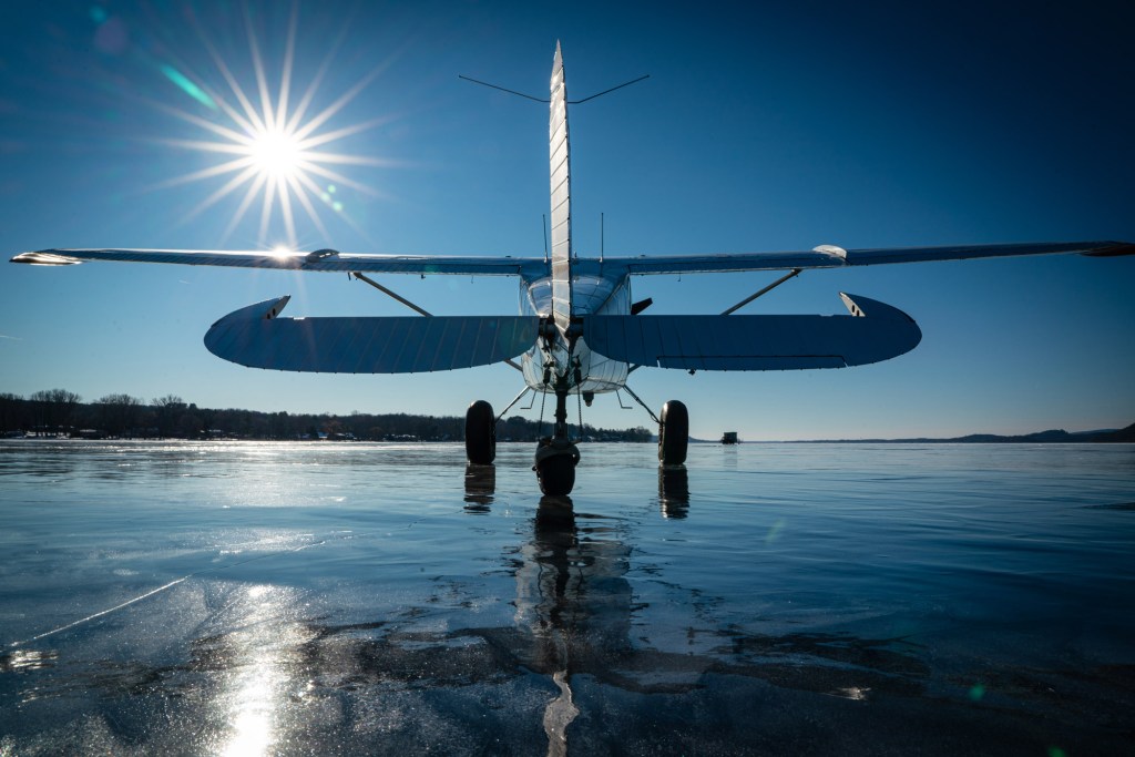 The Cessna 170B, turned toward the sunset, rests on the frozen lake after a successful ice landing. [Credit: Jim Stevenson]