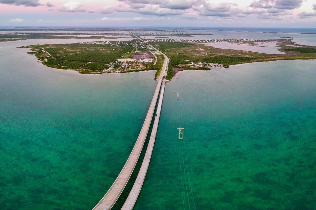 A bird’s-eye view of the Florida Keys showcases turquoise waters, coral reefs, and island chains. [Credit: AdobeStock]